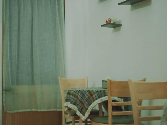 Stół z kraciastym obrusem i drewniane krzesła przy miętowej ścianie z miętową zasłoną w oknie