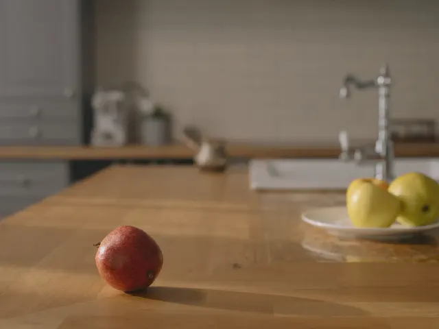 Zbliżenie drewnianego blatu z jabłkami na talerzu, w tle zlew i bateria w stylu retro