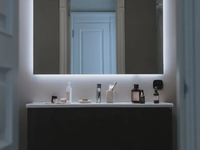 Czarna podwieszana szafka z umywalką i duże lustro z podświetleniem LED w ciemnej łazience