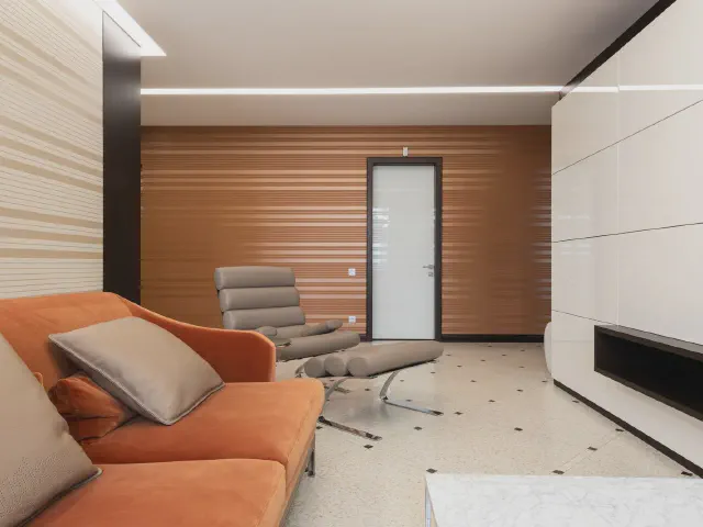 Nowoczesny salon z pomarańczową sofą, szarym fotelem, ścianą w drewnianych pasach i białą zabudową