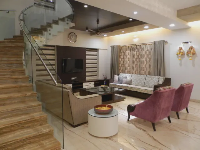 Salon z sofami i fotelami, obok marmurowe schody ze szklaną balustradą i stalową poręczą